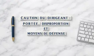 Lettres formant "Caution du dirigeant : portée, disproportion et moyens de défense". Un stylo bleu et un clavier sont visibles.