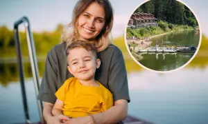 Uśmiechnięta mama z synkiem na pomoście. W tle jezioro z łódkami i domkami, idealne miejsce na wykorzystanie bonu turystycznego.