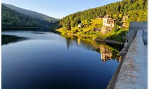 Spokojna tafla jeziora odbija zamek i zalesione wzgórza czeskich Karkonoszy.