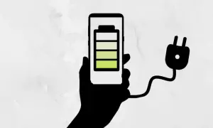 Mano sosteniendo un teléfono con batería a 3/4, conectado a un enchufe. ¡Un truco para el ahorro de batería!