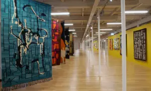 Wystawa prezentuje, kto wytwarza dekoracyjne tkaniny ścienne. Kolorowe, abstrakcyjne wzory zdobią galerię.