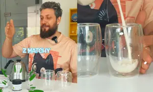 Mężczyzna pokazuje, jak przygotować matcha. Na stole czajnik, proszek matcha i szklanki. Mleko wlewane do szklanki.