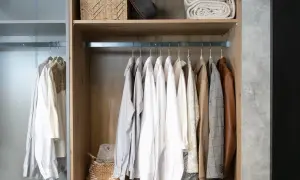 Jak poukładać w szafie? Ubrania wiszą na wieszakach, na półkach kosz i koce.