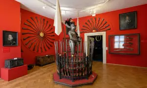 Armure de chevalier et fusils anciens exposés dans une salle rouge vif, un aperçu de l'interieur chateau de Prague.