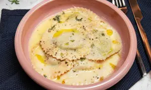 En skål med krämig ravioli, perfekt för ett enkelt ravioli recept. Garnerad med örter och parmesan.