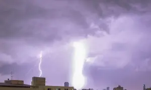 Potężne wyładowanie rozświetla nocne niebo nad miastem. Jaka jest szansa na uderzenie pioruna w dom? Niska, ale burza wygląda groźnie.