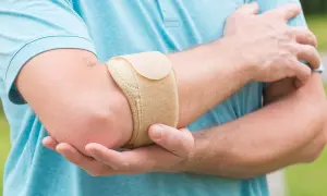 Mann mit Bandage am Ellenbogen, um den **Tennisellenbogen** zu lindern.