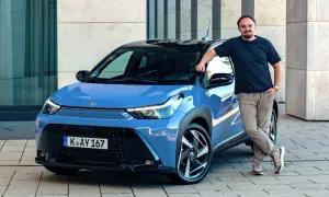 Mężczyzna opiera się o niebieską Toyotę Aygo X Hybrid.