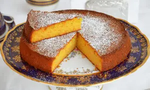 Una deliziosa torta carote e mandorle, spolverata di zucchero a velo, servita su un elegante piatto decorato.