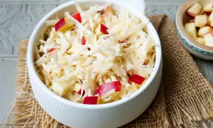 Frischer sellerie salat mit roten Apfelstücken, garniert mit schwarzem Pfeffer, serviert in einer weißen Schüssel auf Jute.