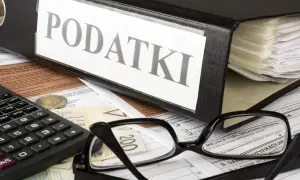 Segregator z napisem "PODATKI", okulary, kalkulator i pieniądze. Kto to jest rezydent podatkowy? To osoba, która musi rozliczyć się z dochodów.