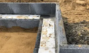 Grunden byggs med lecablock. Sand och grus syns runt den pågående murningen.