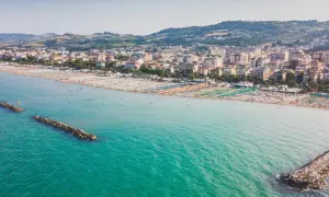 Vista aerea di San Benedetto del Tronto, con il suo lungomare affollato di ombrelloni colorati e il mare turchese.