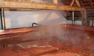 Vapore sale da una grande vasca di rame in una lambiek fabriek. La luce illumina il processo di produzione della birra.