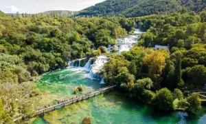 Atemberaubende Wasserfälle im Krka Nationalpark, Kroatien. Eine Holzbrücke führt Besucher über das smaragdgrüne Wasser.