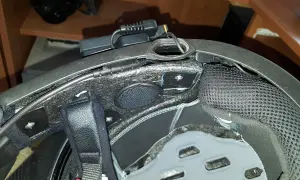Montaż interkomu w kasku motocyklowym. Widoczne przewody i moduł komunikacyjny.