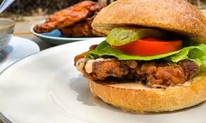 Burger maison au poulet croustillant et juteux, garni de laitue, tomate et cornichon.
