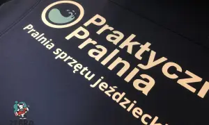 Druk termotransferowy na granatowej odzieży: logo pralni "Praktyczna Pralnia" i napis "Pralnia sprzętu jeździeckiego".