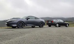Due coupé Honda, una moderna e una classica, si incontrano su una strada di campagna. La nuova Honda Prelude 2026, grigio scuro, spicca accanto alla sua antenata.