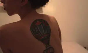 Kolorowy tatuaż balon z małym słoniem na plecach kobiety.