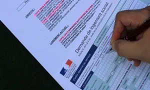 Formulaire de demande de mutation pour un logement social. Un stylo remplit les champs d'une demande de logement social.