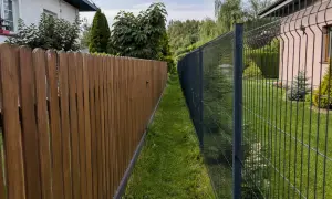 Dwa płoty, drewniany i metalowy, stoją obok siebie. Czy można postawić płot przy płocie? Tak, jak widać na zdjęciu.