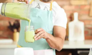Hombre vertiendo un batido verde cremoso, ideal para quienes buscan alternativas a los tipos de leches vegetales.