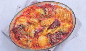 Un gratin patate douce aux tomates et fromage fondant, garni de thym frais, sort tout juste du four.