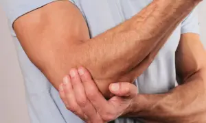 En man håller sin armbåge, som om han har ont i underarmen ovansida.