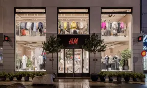 H&M-Filiale bei Nacht. Die Schaufenster zeigen Kleidung, die das Konzept von H&M als Fast Fashion widerspiegelt.