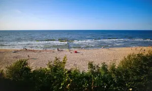 Słoneczna plaża, morze i ludzie spacerujący brzegiem. Dziwnówek atrakcje to idealne miejsce na letni wypoczynek.