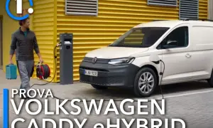 Un uomo porta cavi per caricare il Volkswagen Caddy eHybrid, un furgone bianco parcheggiato vicino a una stazione di ricarica.
