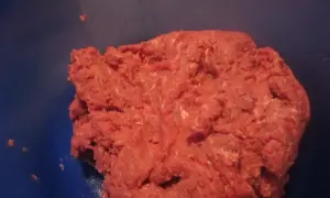 Frisches Hackfleisch, frisch gewolft, bereit für die Zubereitung von Frikadellen. Das gewolft bedeutungsvolle Fleisch liegt in einer blauen Schüssel.