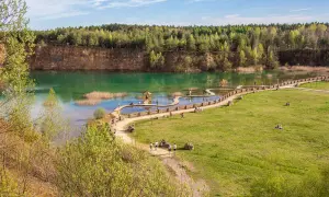 Malowniczy park Gródek w Jaworznie z turkusową wodą, drewnianymi kładkami i zielonymi terenami rekreacyjnymi.