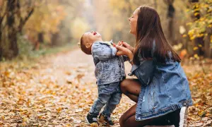Mamma e figlio ridono felici in un bosco autunnale. Le loro risate sono come le più belle frasi madre figlio.