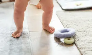 Małe stópki na ciepłej podłodze. Czy ogrzewanie podłogowe jest zdrowe dla maluchów? Miękkie dywany i zabawki zachęcają do pierwszych kroków.