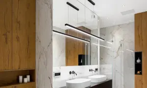 Bagno moderno con lavabi bianchi, specchio ampio e moderne idee illuminazione bagno con lampade a sospensione nere.