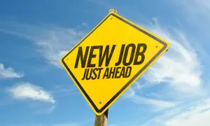 Gul varningsskylt med texten "NEW JOB JUST AHEAD" mot en blå himmel med moln. Perfekt för den som trivs inte på jobbet och söker nya utmaningar.
