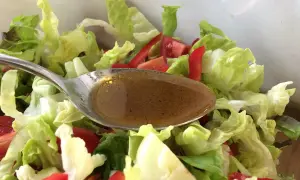 Löffel mit balsamico dressing über frischem Salat mit Tomaten und Paprika.