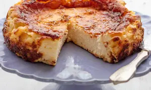 Tarta de queso de la Viña, dorada y cremosa, servida en un plato morado.