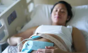 Une femme enceinte est allongée, un moniteur de rythme cardiaque fœtal est fixé sur son ventre. Ce monitoring sert à surveiller le bien-être du bébé.