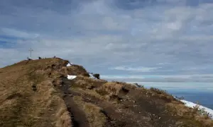 Pfad führt zu einem Gipfelkreuz auf einem **hohen Freschen**. Wanderer genießen die Aussicht auf die Alpen.