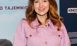 Uśmiechnięta Natalia Sisik w różowej kurtce, z kolorowym naszyjnikiem.