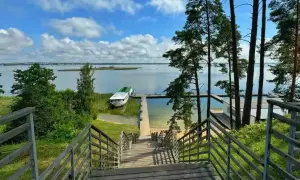 Idealne miejsce na mazury na weekend. Drewniane schody prowadzą do jeziora, gdzie cumuje statek.