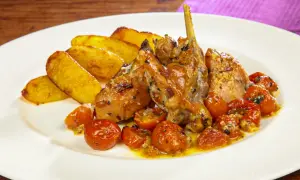 Piatto di coniglio al forno con patate arrosto e pomodorini confit.