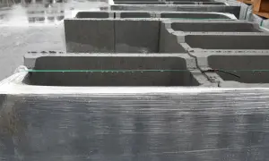 Stos betonowych bloczków zalewowych, owiniętych folią, czeka na budowę.