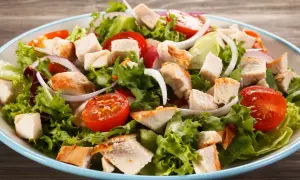Insalata di pollo fresca con lattuga croccante, pomodorini succosi, cipolla rossa e pezzi di pollo grigliato.