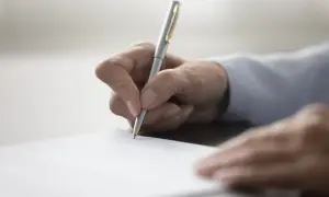 Dłoń pisze długopisem na papierze. To ważny moment, gdy zastanawiasz się, jak napisać testament.