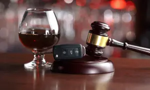 Kielich z alkoholem, kluczyki do auta i młotek sędziowski symbolizują samoukaranie za jazdę po alkoholu.