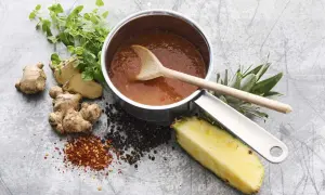En kastrull med sötsur sås som på kinarestaurang, med ingefära, ananas, pepparkorn och chiliflakes.
